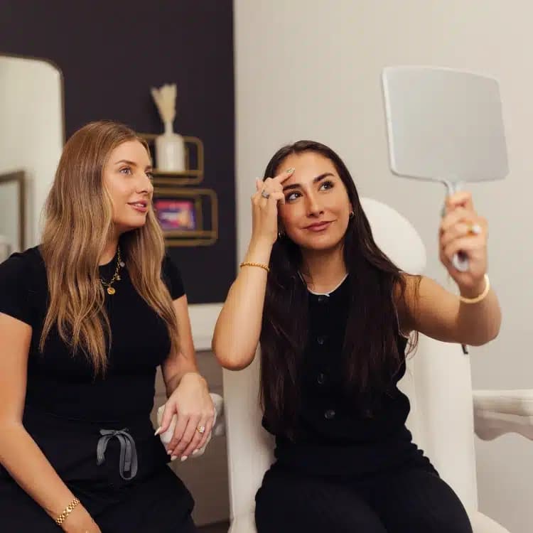 CoolPeel consultation with two women checking skin results in mirror during aesthetic treatment appointmen