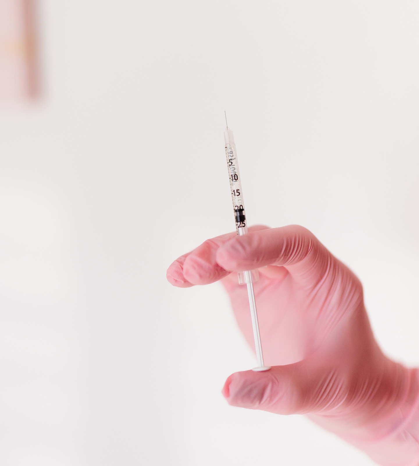 woman in pink gloves holding botox needle
